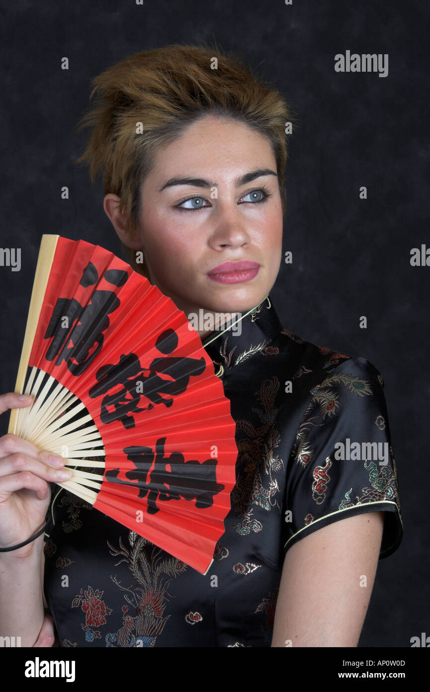 Portrait d'une jeune femme dans une robe chinoise avec un ventilateur rouge Banque D'Images