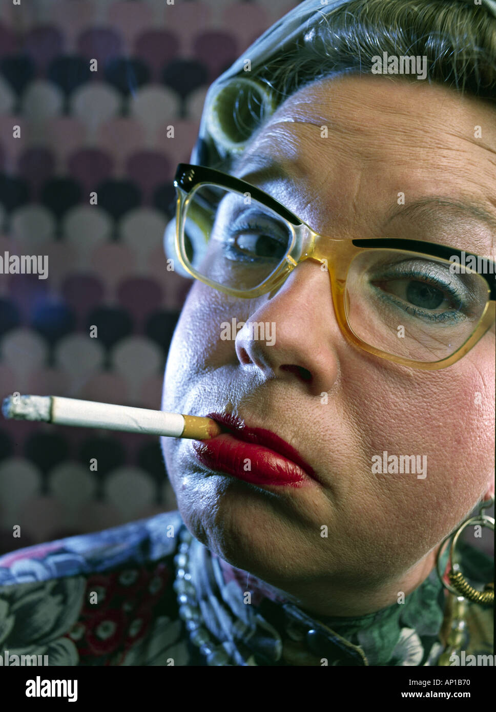 Femme avec friser sur sa tête et lunettes fumer une cigarette MR Model Publié Banque D'Images