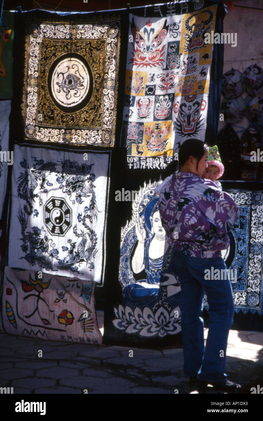 Femme portant son enfant passé un décrochage de l'arrière allumé quilts en vente,Chengdu, Sichuan Province, China. Banque D'Images