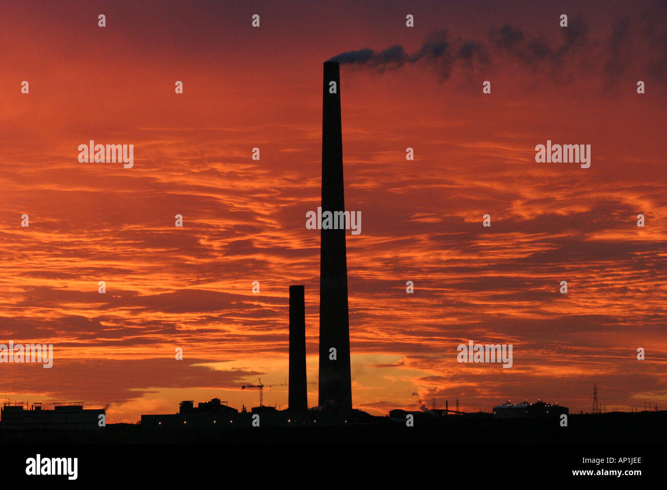 La formation de nuages coucher de soleil ardent par les cheminées industrielles Banque D'Images