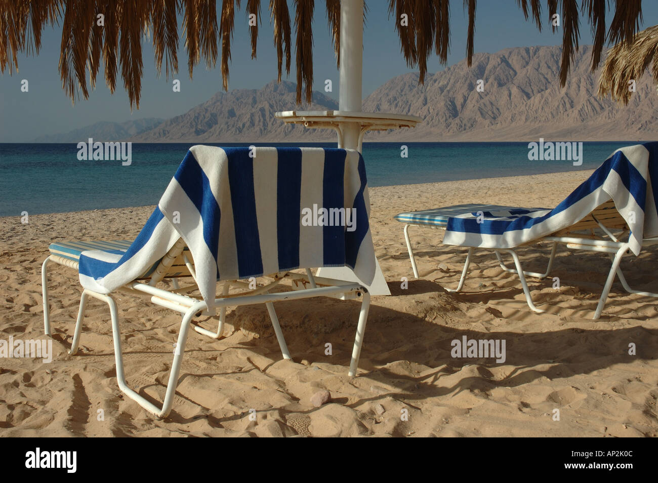 Deux chaises longues de plage serviettes à rayures préparé pour une journée au soleil sur la plage Banque D'Images