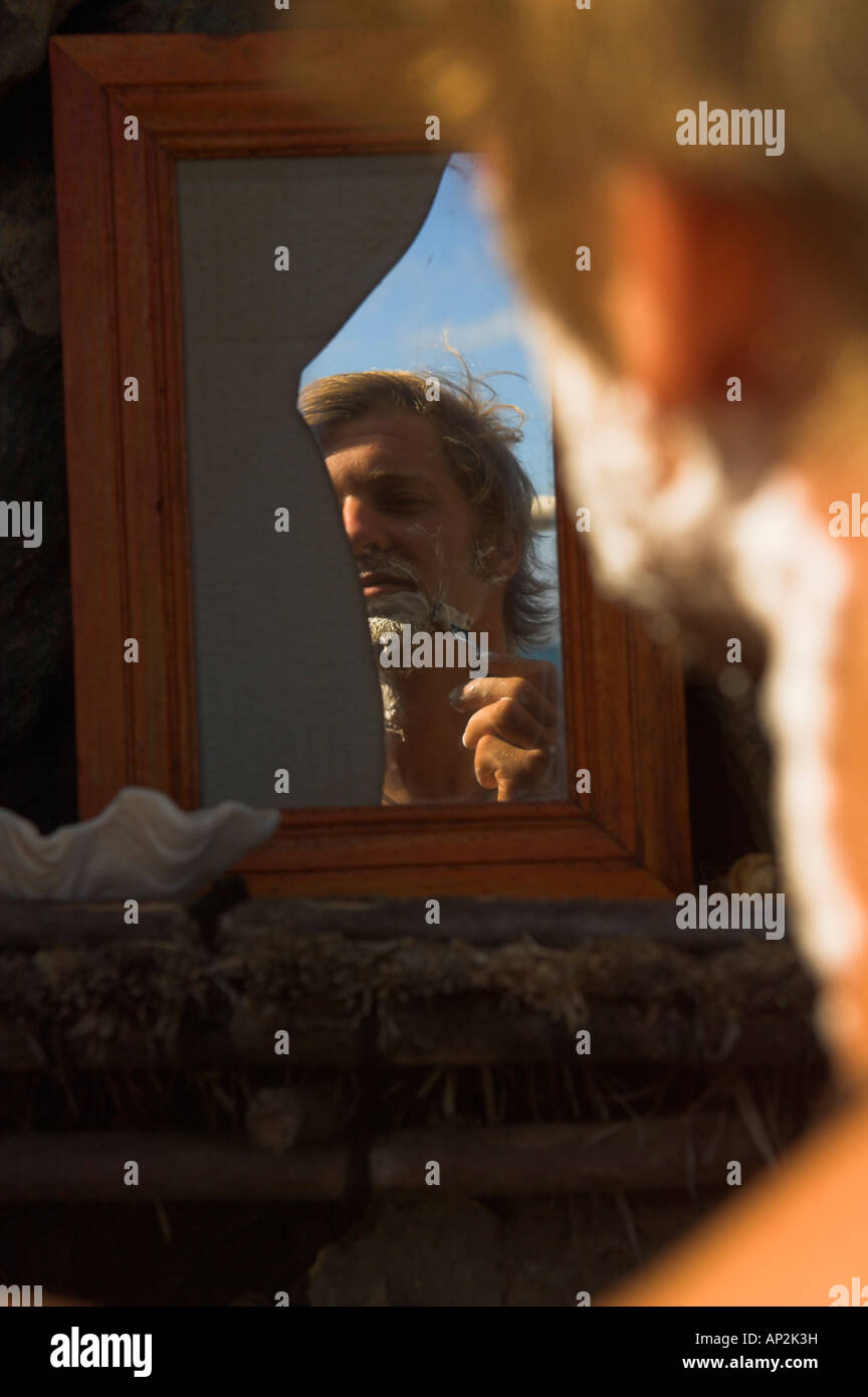 La réflexion d'un homme le rasage dans un miroir brisé, Madagascar, Afrique Banque D'Images