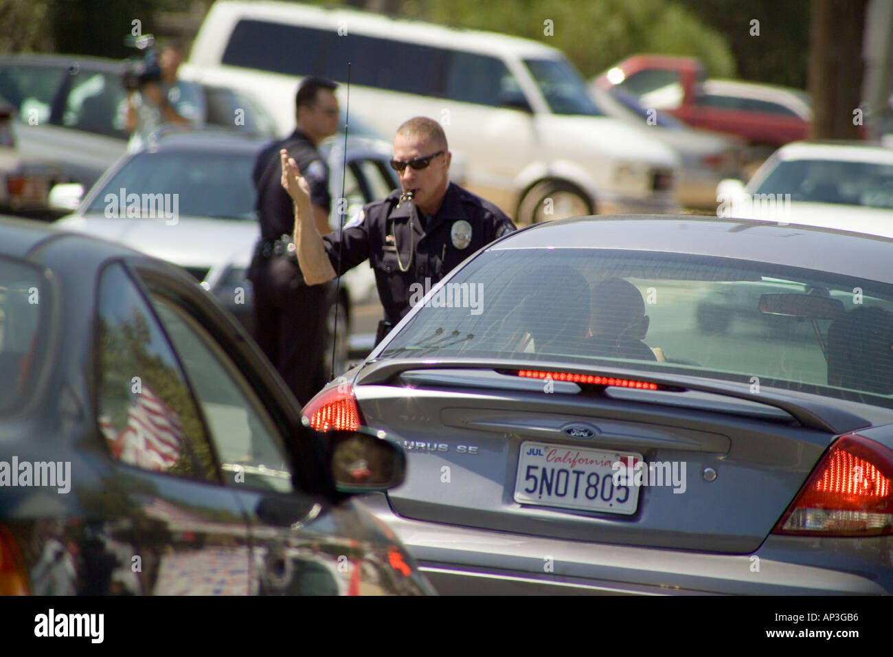 La tenue d'un sifflet dans sa bouche un policier dirige le trafic de poids lourds dans la région de Laguna Beach en Californie Banque D'Images