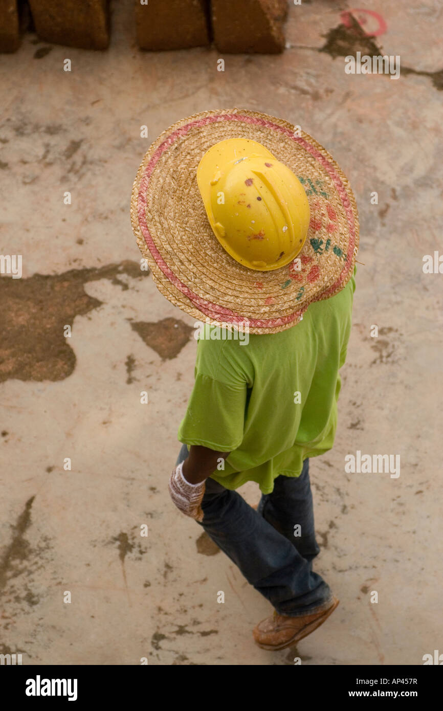 Un travailleur sur un chantier de la Malaisie porte un chapeau de paille,  pour l'ombre, sous son casque de sécurité Photo Stock - Alamy