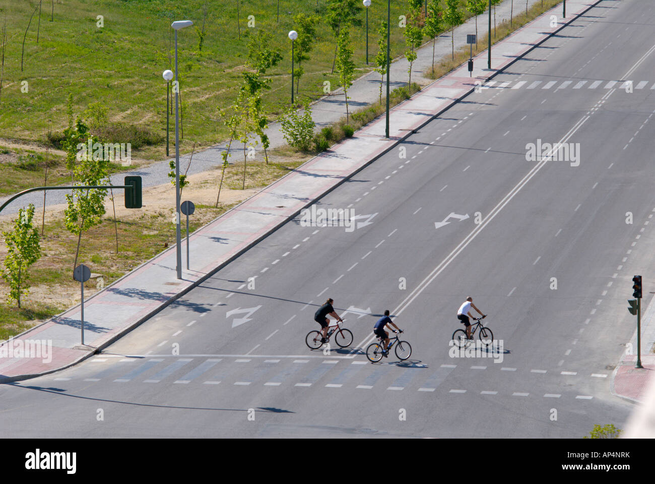 Trois cyclistes roulent sur une autoroute déserte crossing Banque D'Images