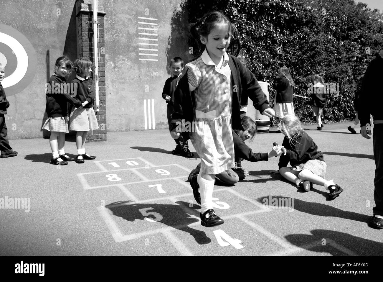 L'école primaire des enfants jouant à la marelle Junior en aire de jeux Banque D'Images