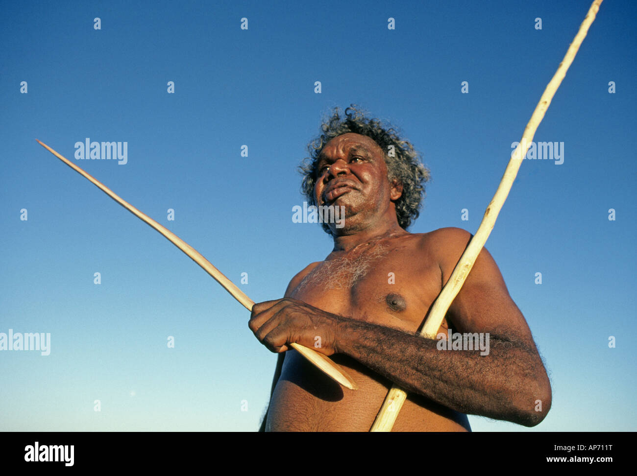 Un aborigène australien avec killing stick et boomerang près de Ayers Rock ou Uluru dans les Territoires du Nord dans le centre de l'Australi Banque D'Images