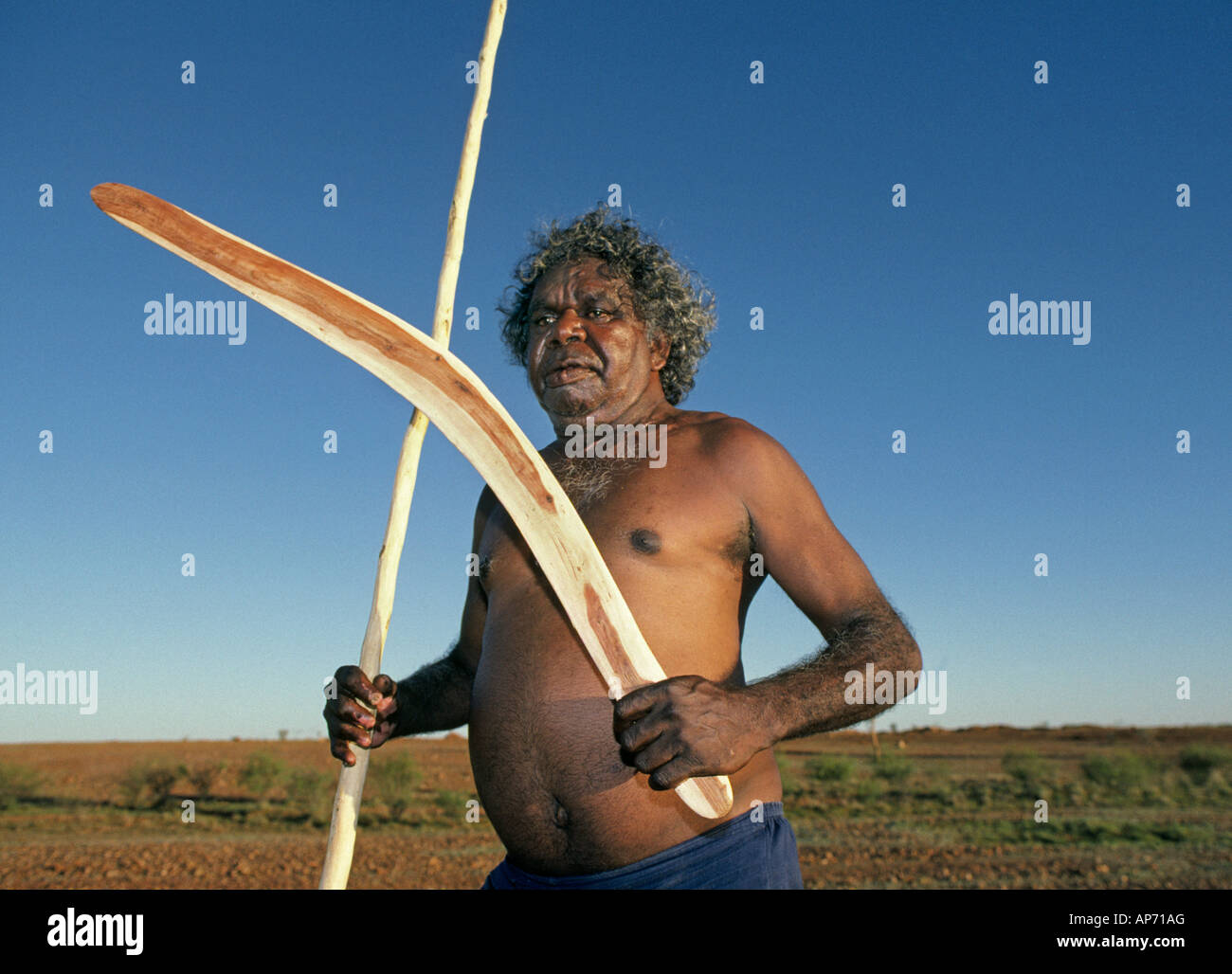 Un aborigène australien avec boomerang et tuant stick dans l'Outback près de Ayers Rock dans le Nord de l'Australie Banque D'Images