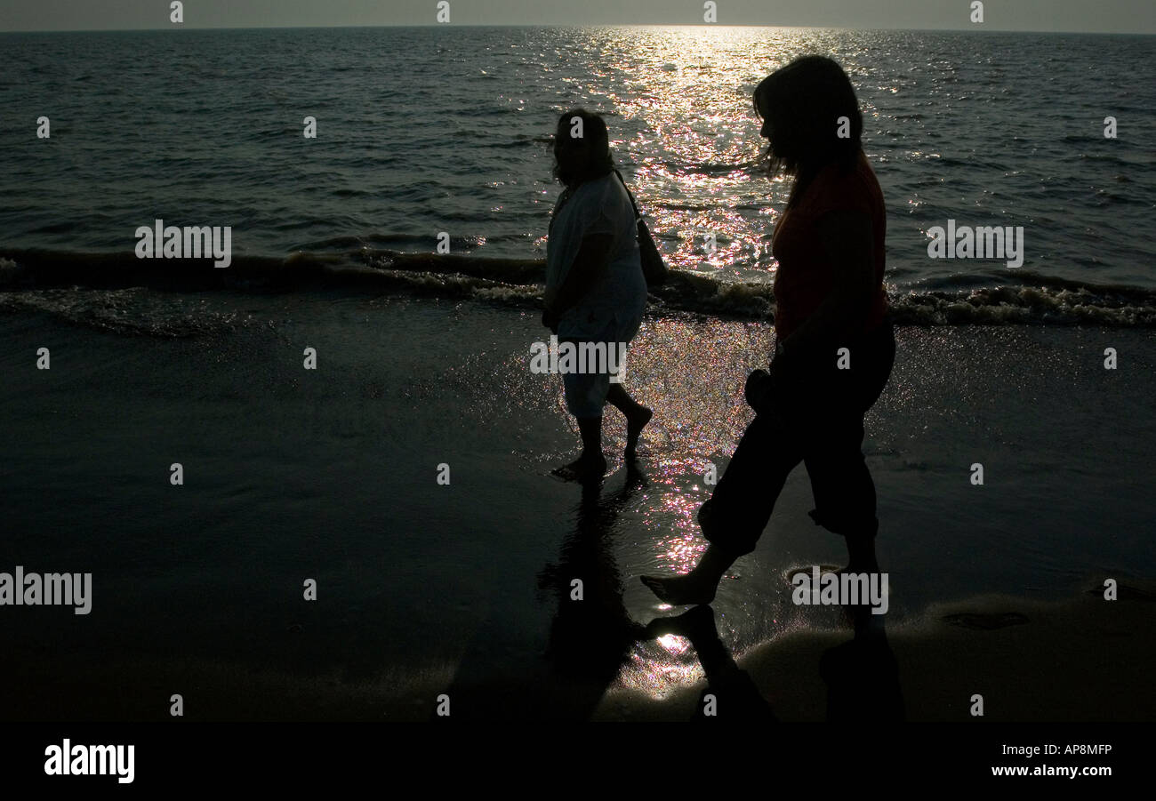 Deux personnes à pied par la mer tandis que les couchers de soleil en Inde Banque D'Images Deux personnes à pied par la mer tandis que les couchers de soleil en Inde Banque D'Images