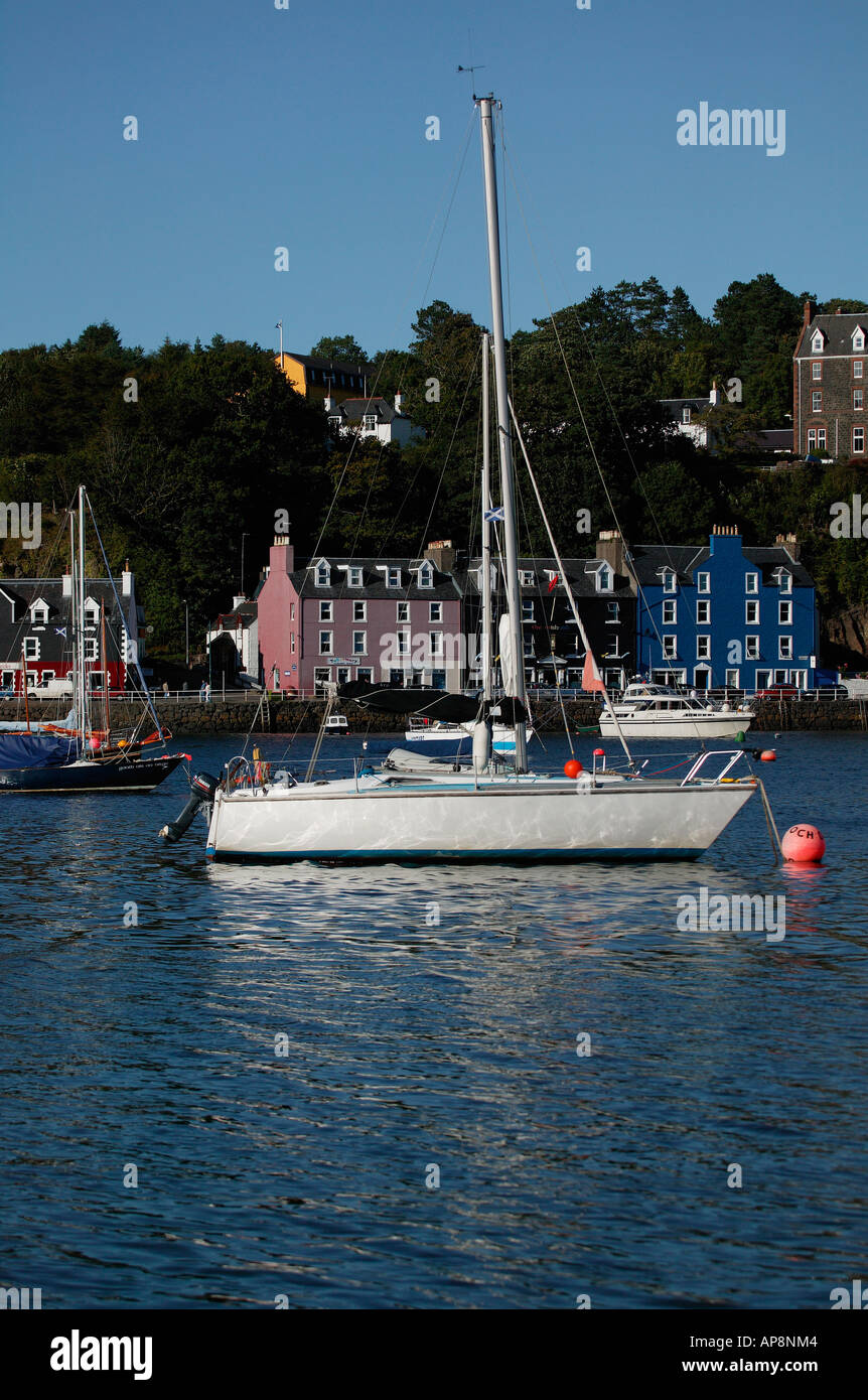 Yacht blanc en premier plan avec des maisons aux couleurs vives de Tobermory, Isle of Mull en arrière-plan, Sound of Mull, Ecosse Banque D'Images