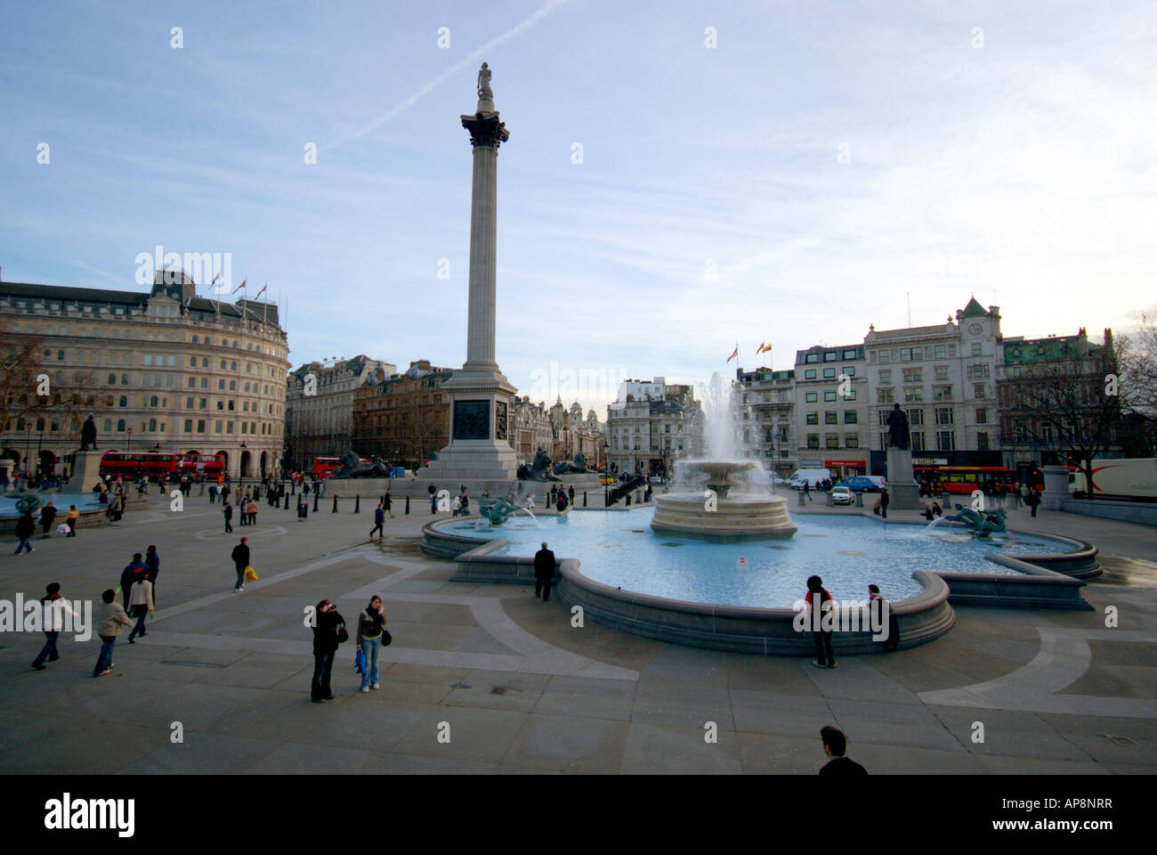 Les gens autour de la mouture à Trafalgar Square avec colonne Nelson et les fontaines. Banque D'Images
