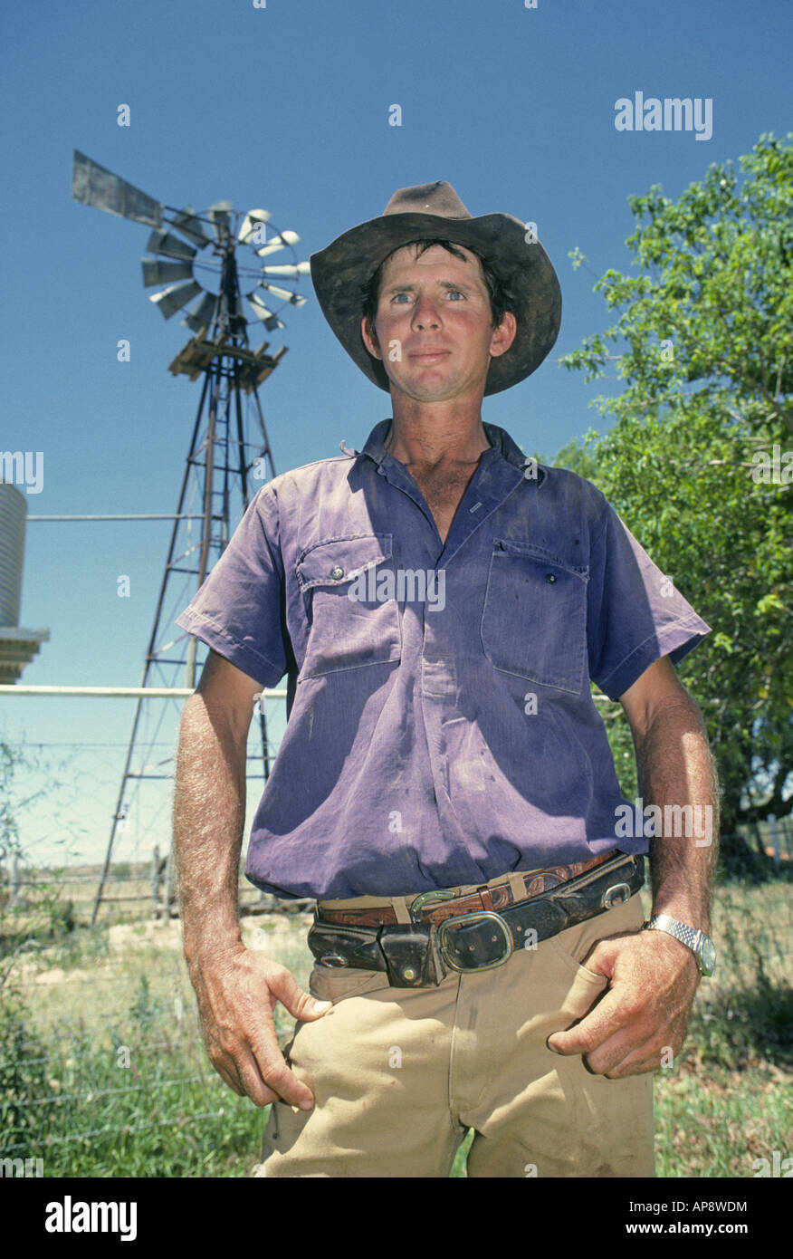 Le portrait d'un cow-boy australien en face d'un moulin à vent sur une grande station de bovins dans l'Outback du Queensland Banque D'Images