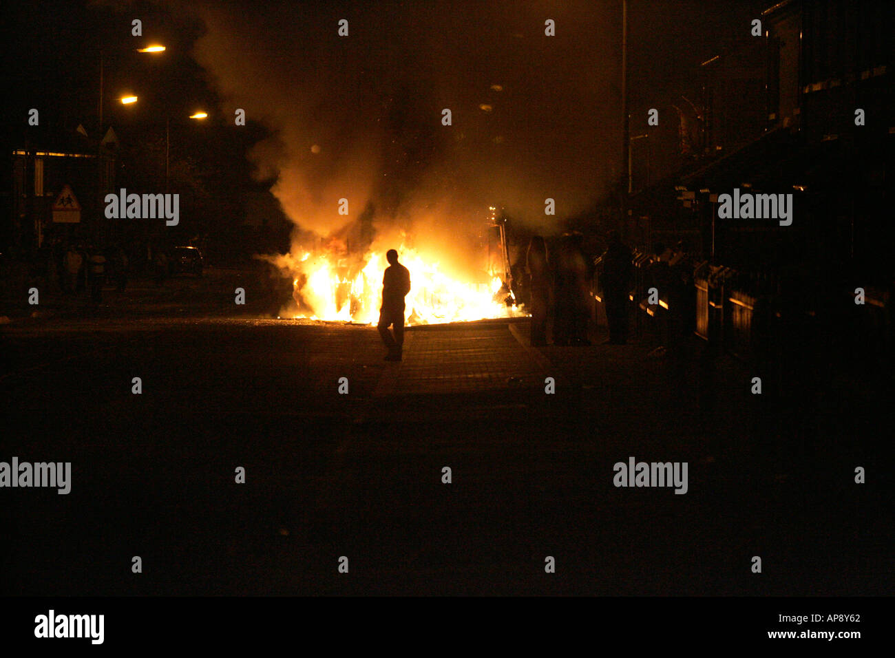 Homme marche en avant du bus en feu sur Cambrai street Belfast lors des émeutes loyalistes d'Irlande du Nord Belfast Banque D'Images