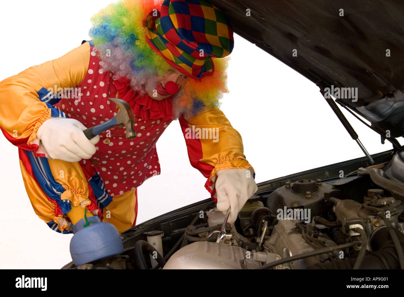 Un clown s'essaie à l'entretien automobile Banque D'Images