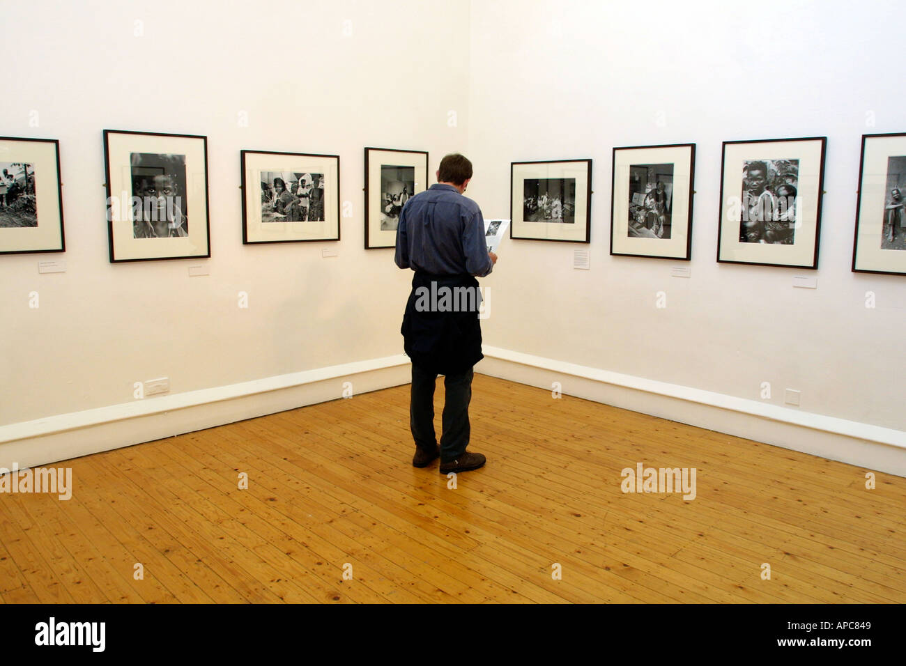 Man looking at art gallery catalogue avec photographies accrochée au mur Banque D'Images