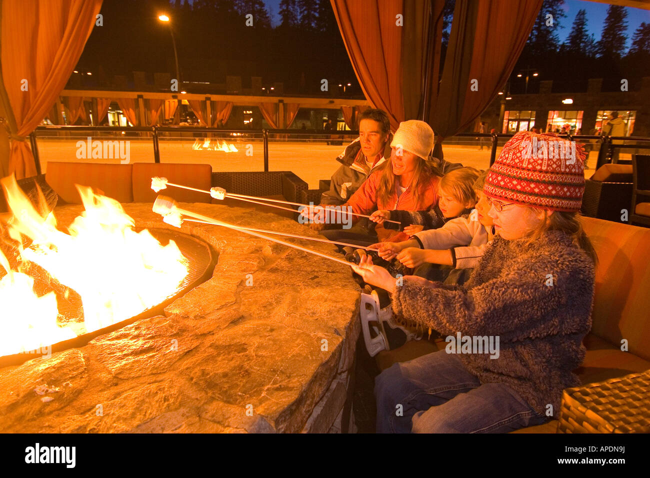 Une famille s'assoit autour d'un feu de guimauves grillées par une patinoire à Northstar station de ski près du lac Tahoe en Californie Banque D'Images