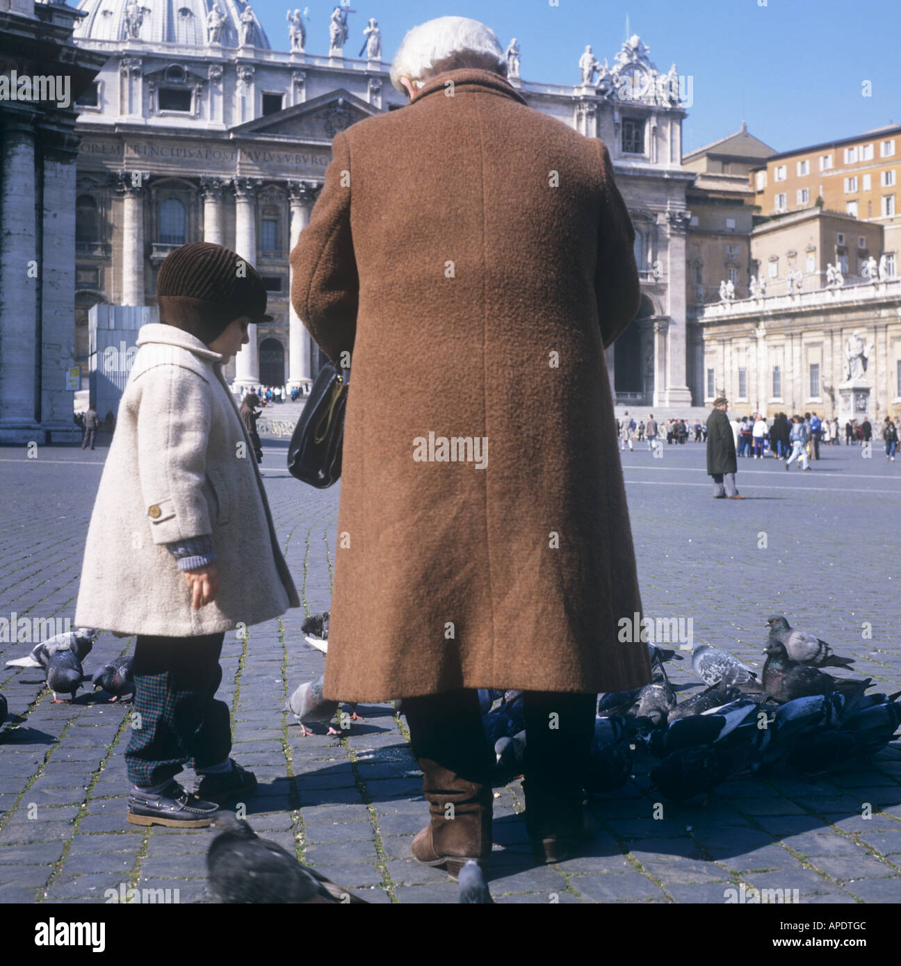 Petit enfant et grand-parent dans les vêtements d'hiver nourrir les pigeons, St Mark's Square, Rome, Italie Banque D'Images