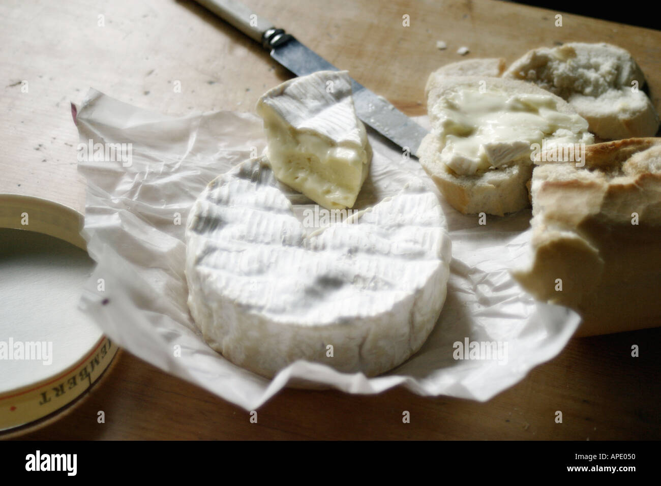 Petit camembert à boîte ouverte et coupées en cadre rustique, avec du pain et ustensiles etc diffusés sur les points saillants des bougies de préchauffage Banque D'Images