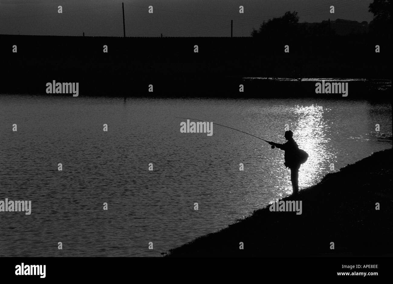 Angler silhouetté contre le soleil la pêche dans un réservoir près de Macclesfield Banque D'Images