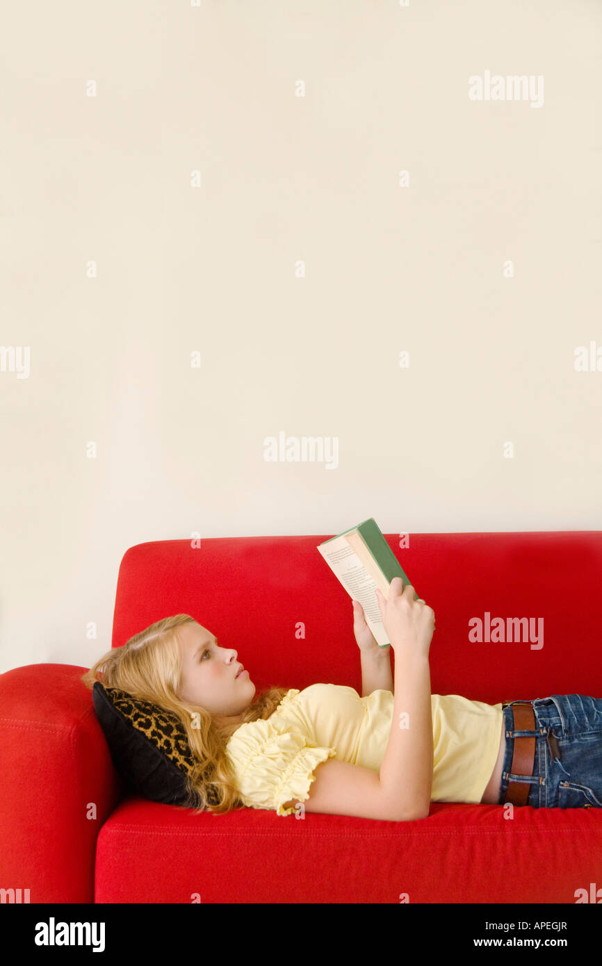 Teenage girl reading on sofa Banque D'Images