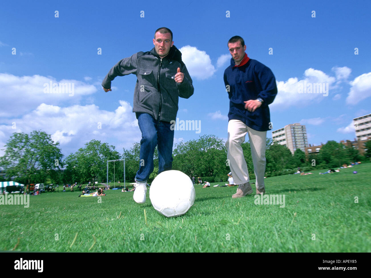 Les hommes chassant le football sur terrain urbain Banque D'Images