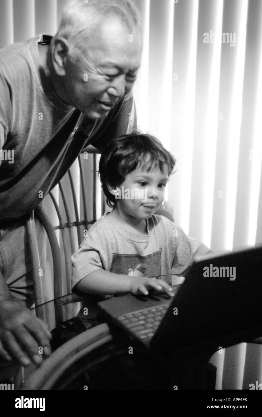 4 ans garçon homme asiatique âgé montrant comment utiliser l'ordinateur portable. B&W. La verticale Banque D'Images