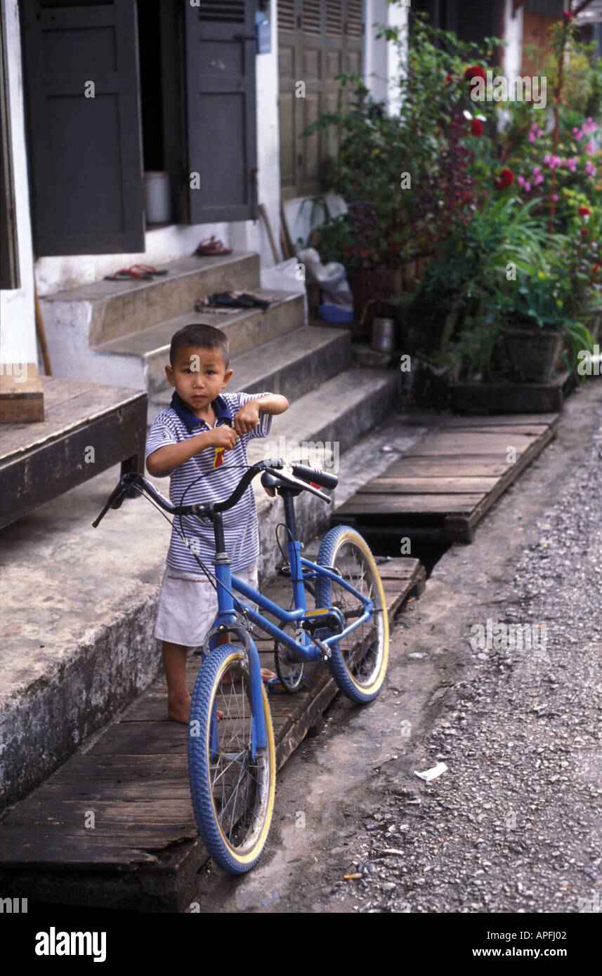 Un garçon et son vélo dans les rues de Luang Prabang, Laos Banque D'Images