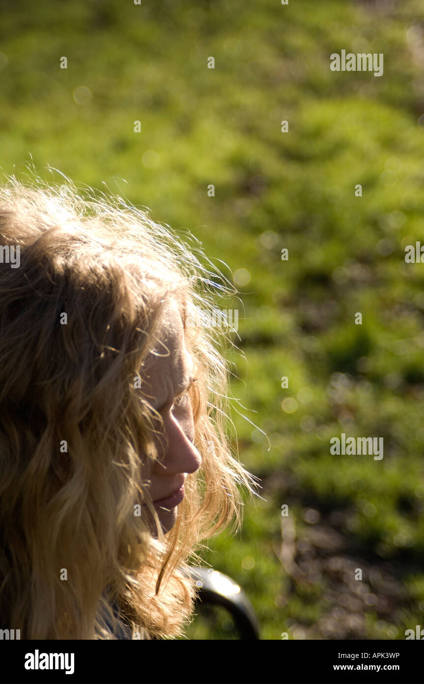 Jeune femme blonde solitaire seul dehors la lumière du soleil qui brille sur ses cheveux Banque D'Images
