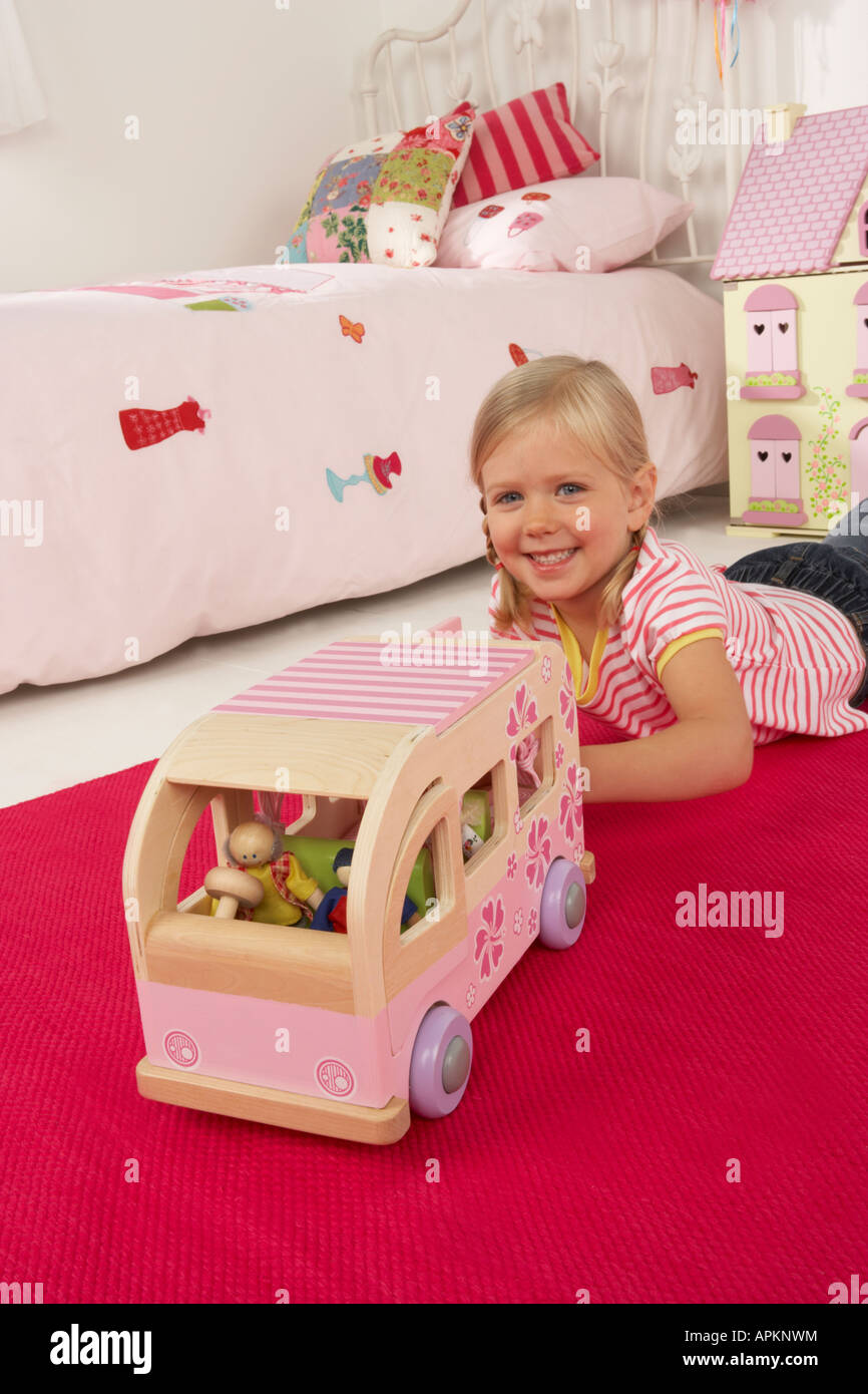 Une fille joue dans sa chambre avec un jouet campervan Banque D'Images