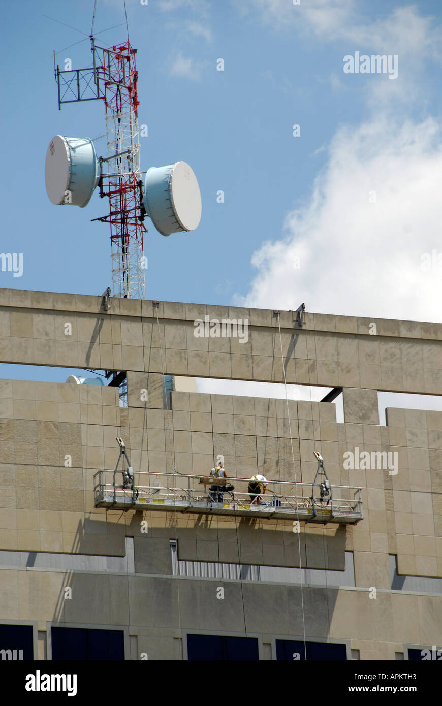 Workman sur le côté d'un immeuble de faire les réparations d'échafaudage est un travail dangereux Banque D'Images