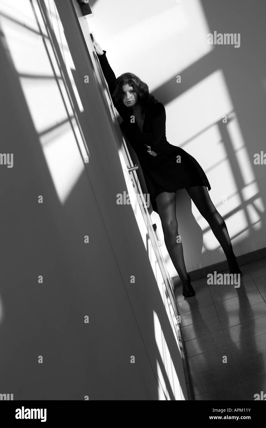 Jeune femme avec robe noire élégante posant dans le hall Banque D'Images