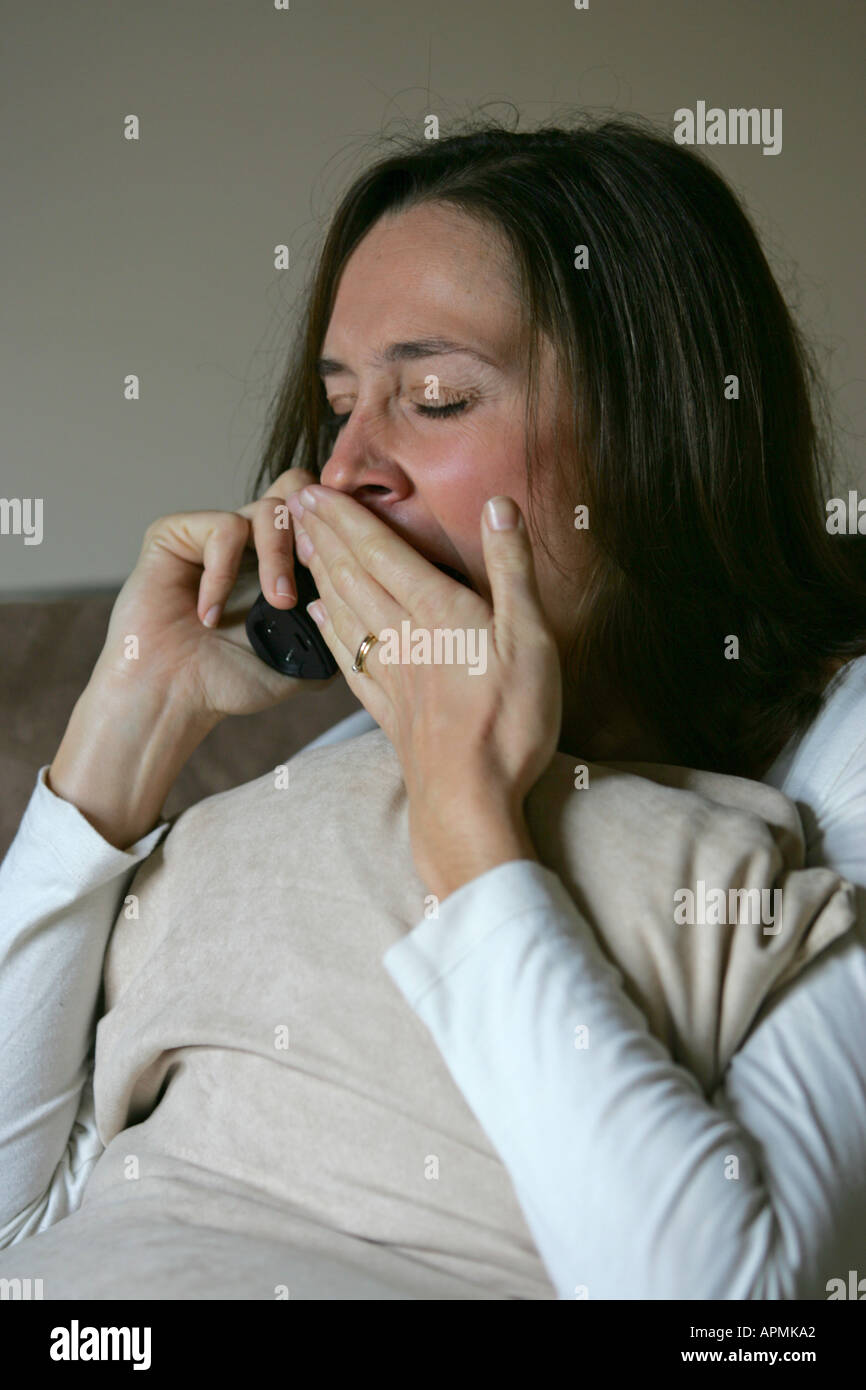 Young 20s 30s brunette woman bâille d'ennui de la fatigue lors d'une conversation téléphonique tout en vous relaxant à la maison Banque D'Images