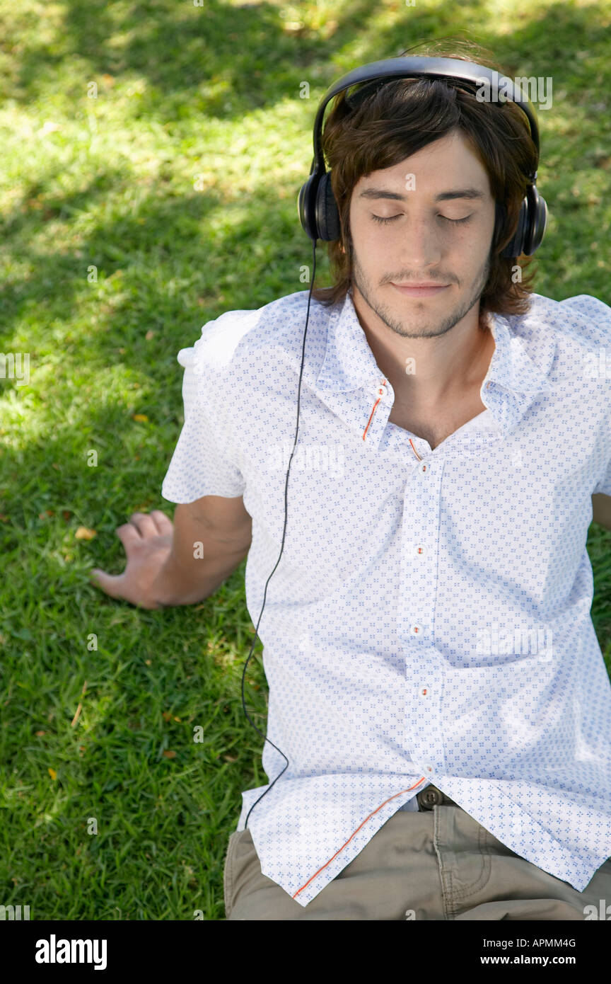 Young man listening to headphones on grass Banque D'Images