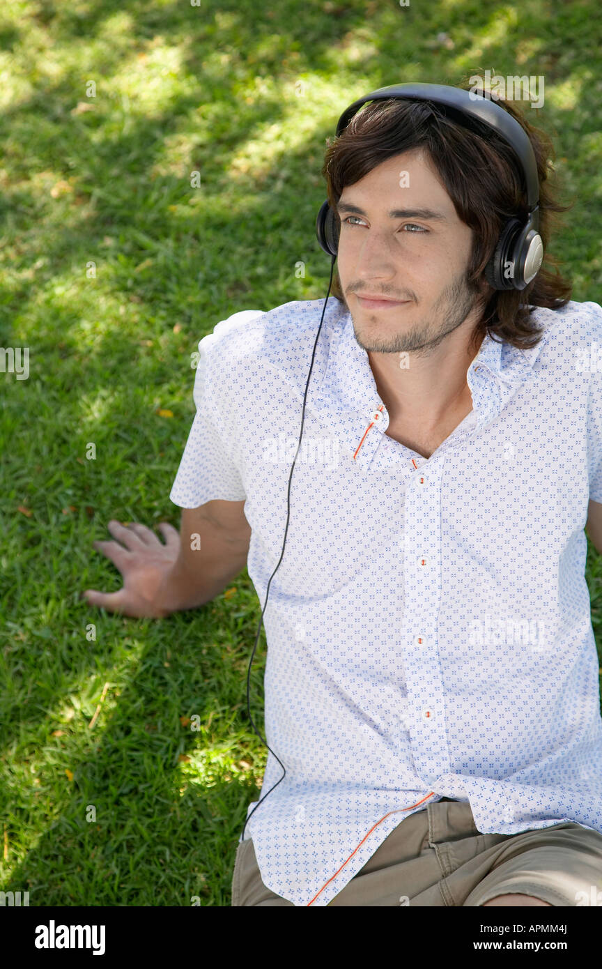 Young man listening to headphones on grass Banque D'Images