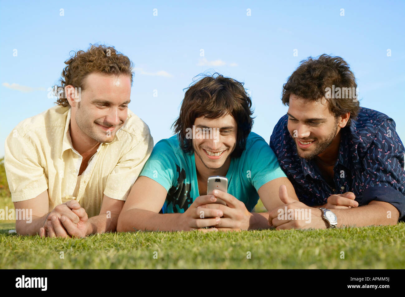 Les jeunes hommes à la recherche de téléphone cellulaire sur l'herbe Banque D'Images