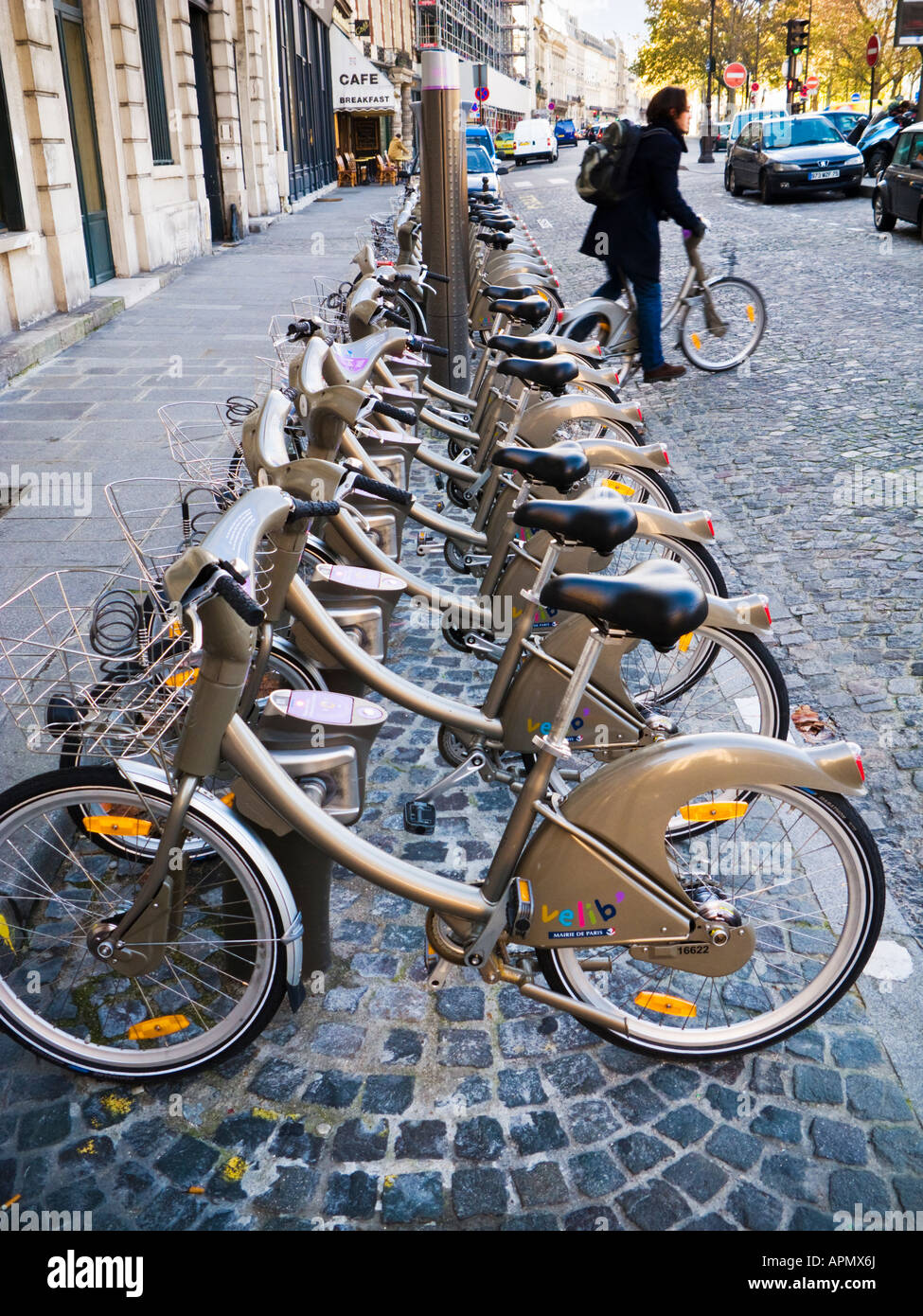 Velib, Paris - cycliste se déplace loin d'un porte-vélos Velib avec des vélos à louer à Paris, France Banque D'Images