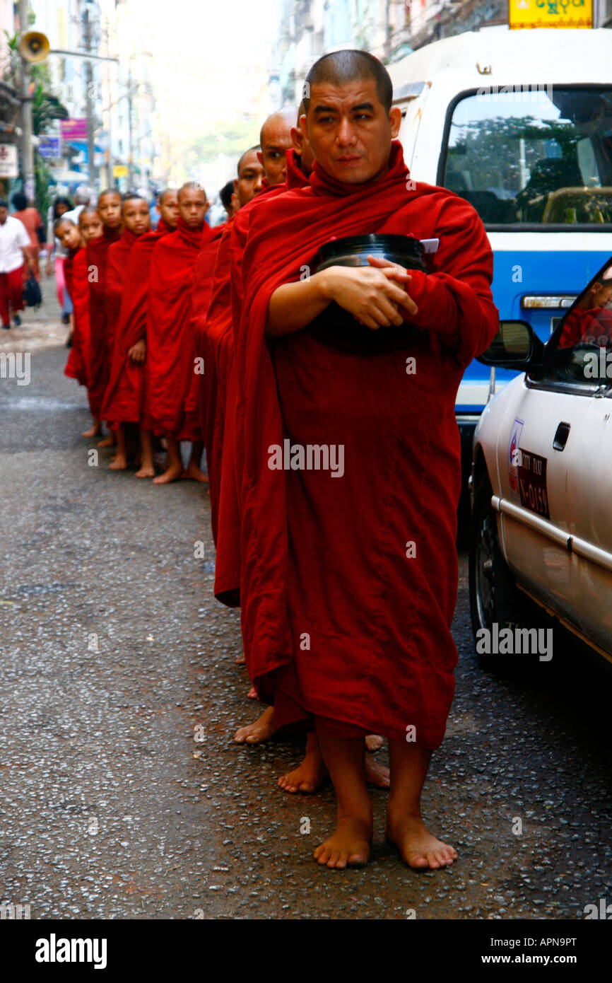 Une file d'attente de moines bordent la rue - recevoir des aumônes à Rangoon (Yangon), la Birmanie (Myanmar) Banque D'Images