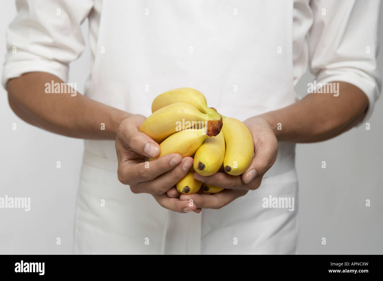 Chef holding régimes de bananes (mid section) Banque D'Images