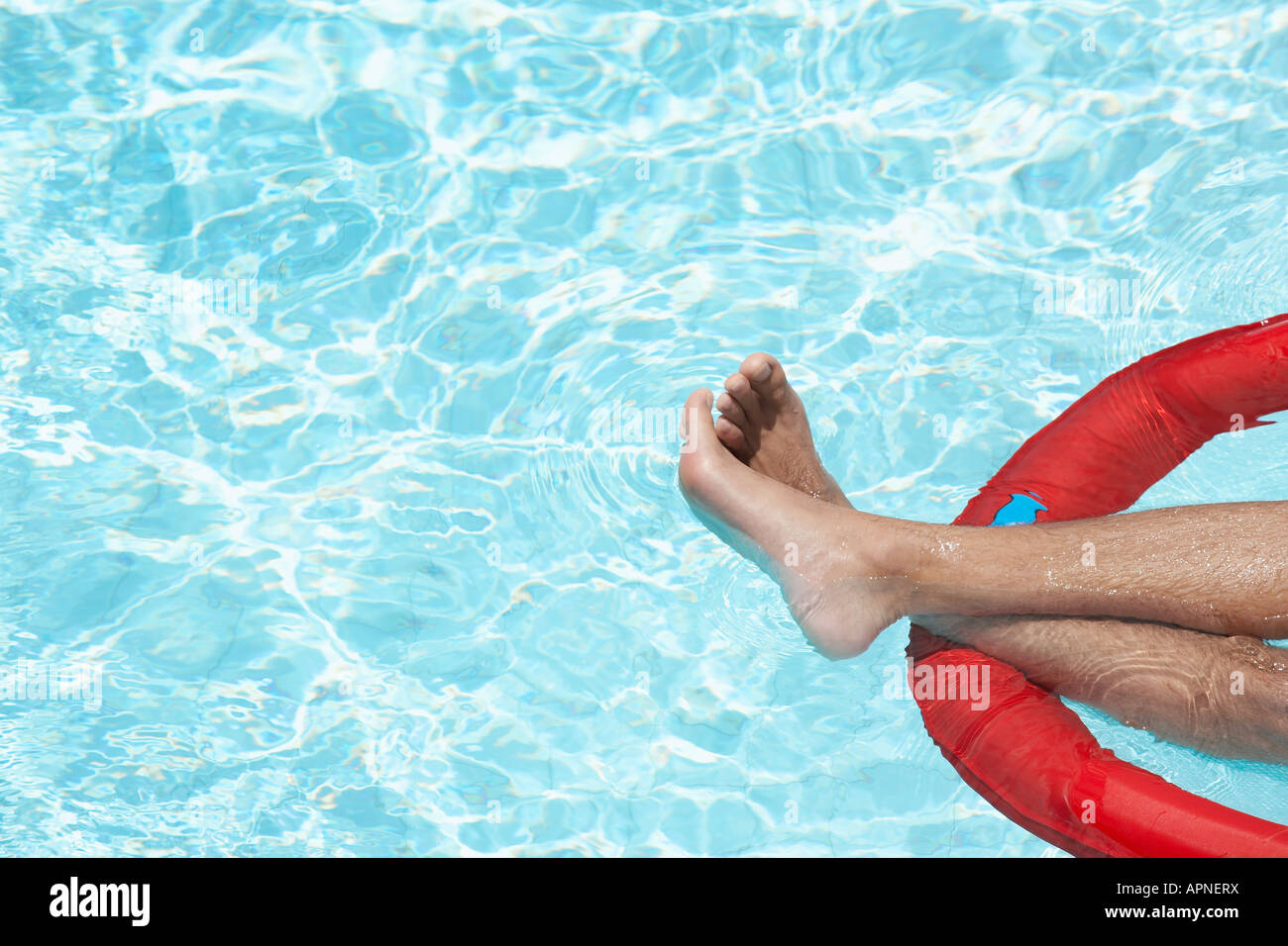 Les jambes de l'homme sur le matelas gonflable dans la piscine Banque D'Images