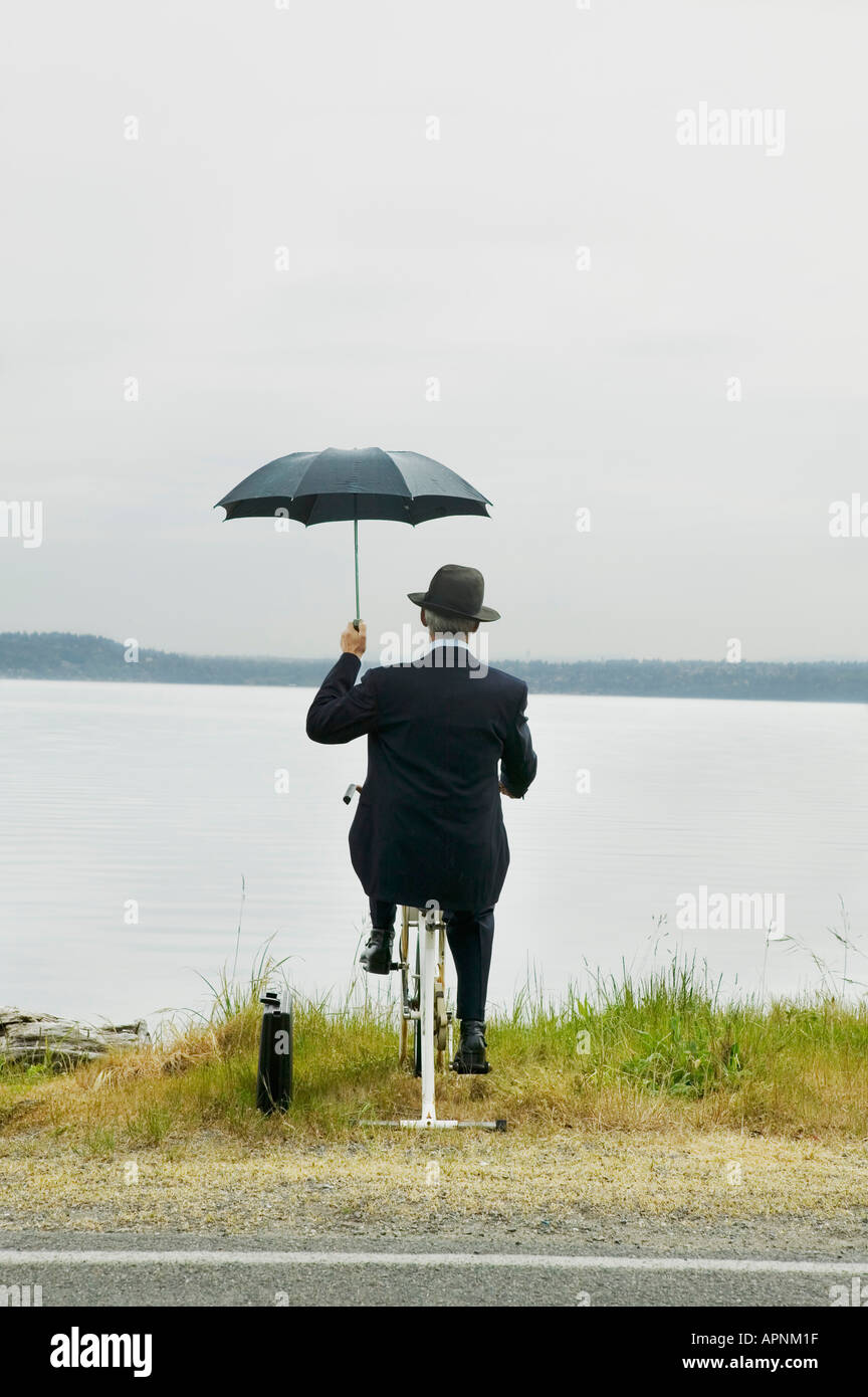 Businessman riding stationary bike par lake Banque D'Images