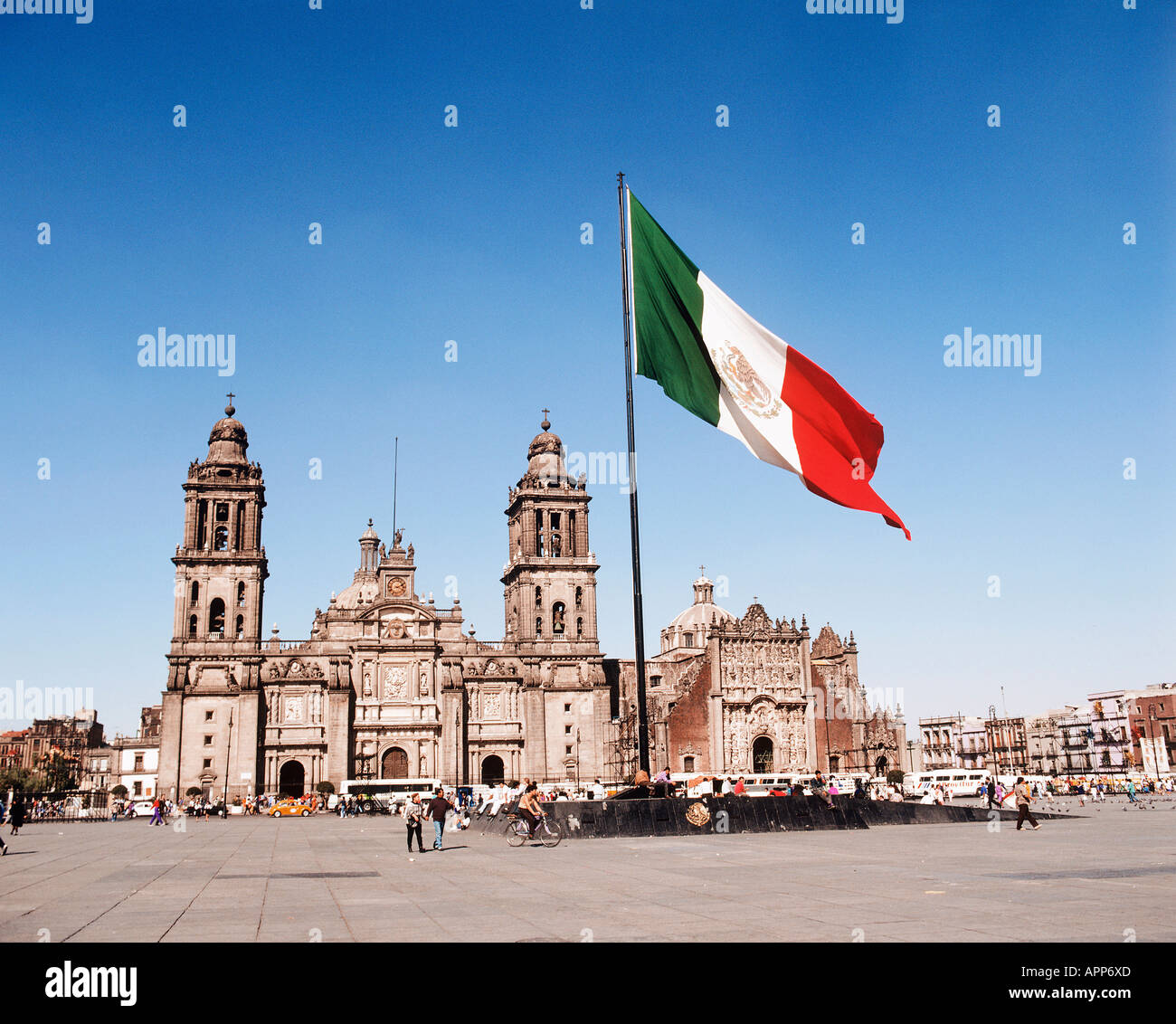 Les voitures et les bus touristiques sur Mexico Zocalo Plaza s avec le drapeau national du Mexique dans le centre et la Cathédrale qui est construit en pierre de basalte gris et lui donnant une vibrante ocre rosé à l'arrière-plan Banque D'Images