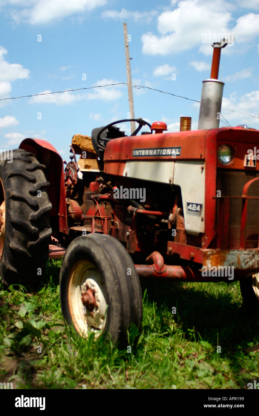 Équipement agricole tracteur bineuse la récolte de l'herbe verte rural blue sky clouds pneu rouge antique antique tondeuse John Deer charrue Banque D'Images