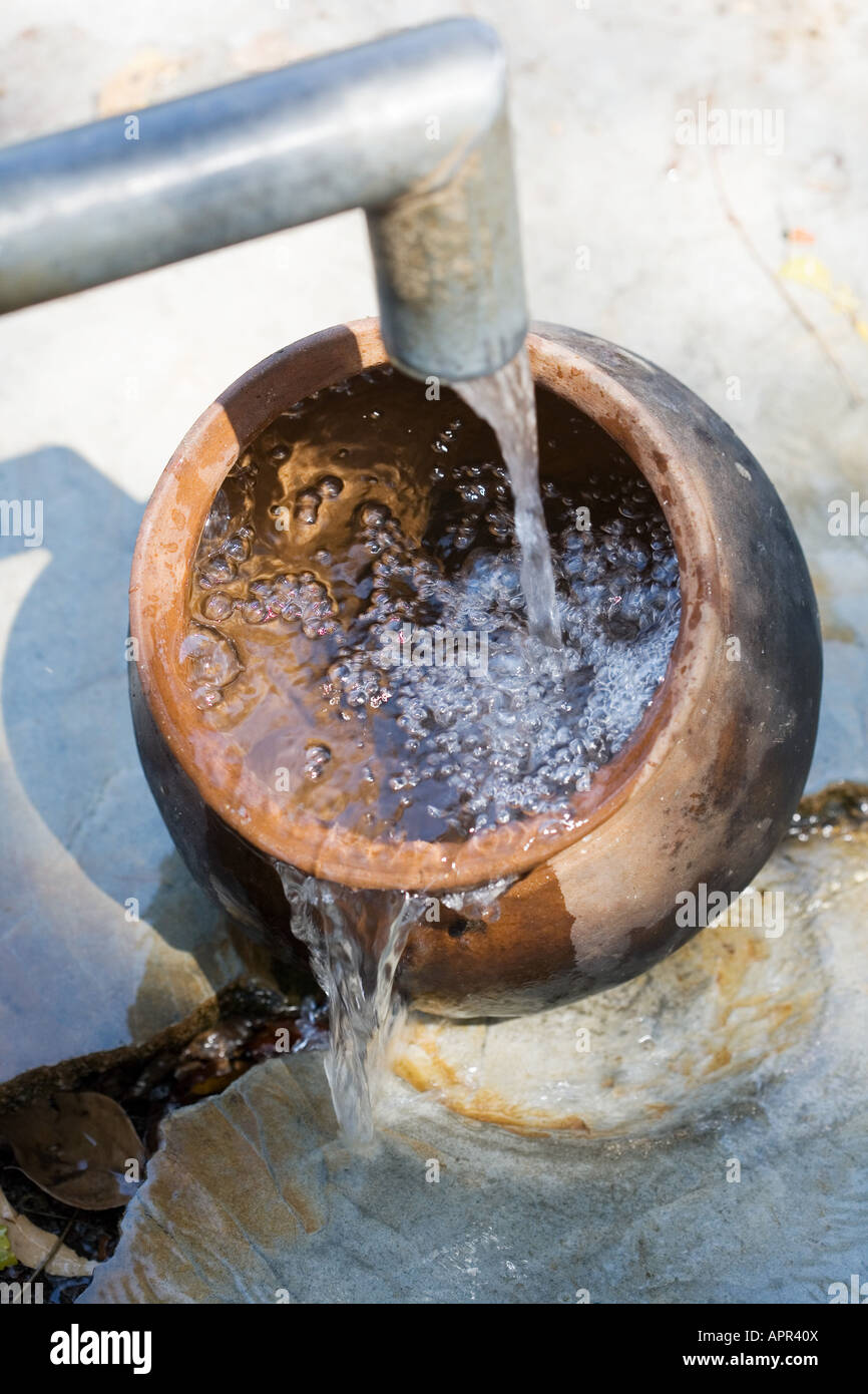 Remplissage d'un pot en argile avec de l'eau à une pompe à main dans la campagne indienne. L'Andhra Pradesh. L'Inde Banque D'Images