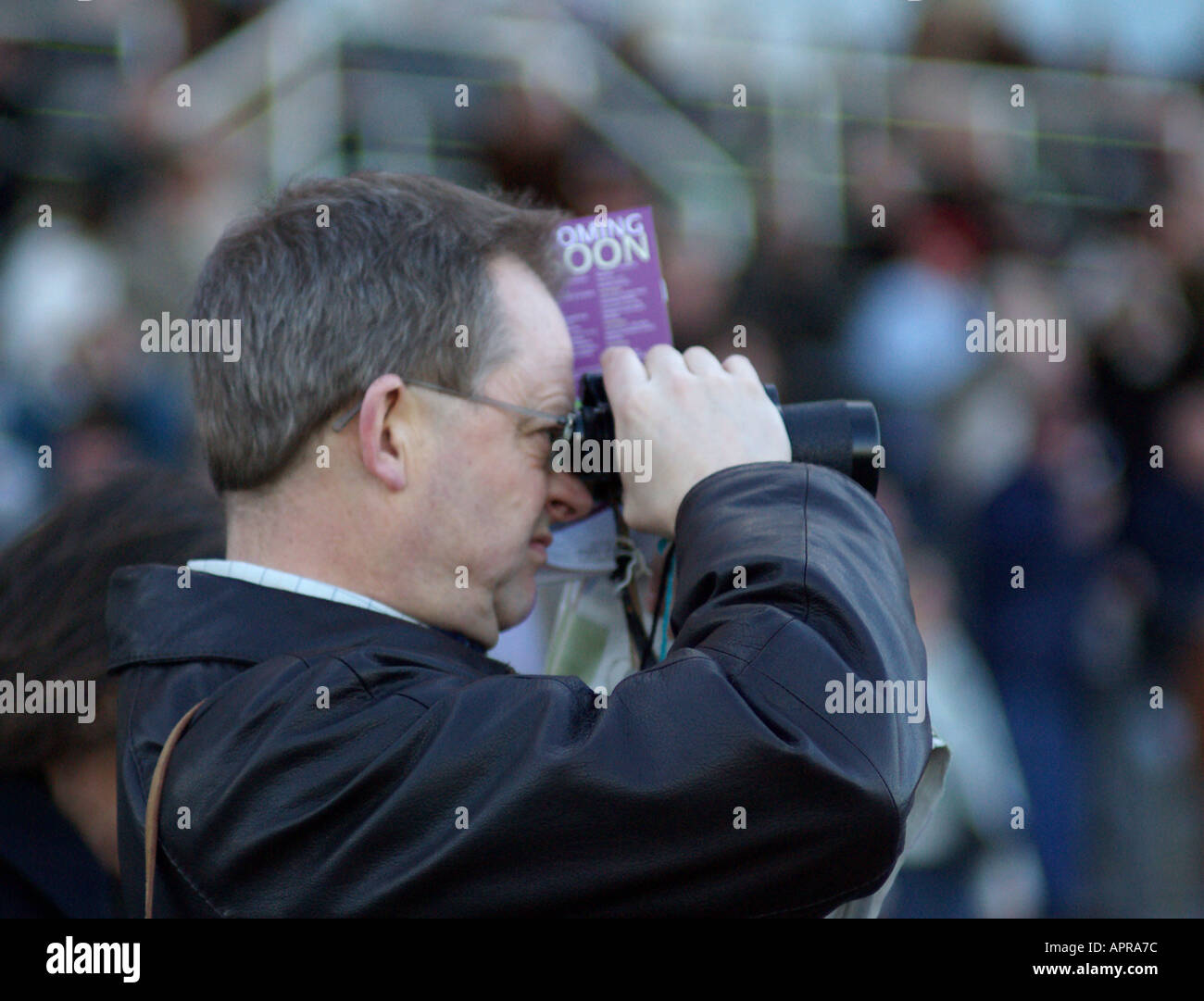 Un homme avec des jumelles à Sandown Park racecourse Banque D'Images