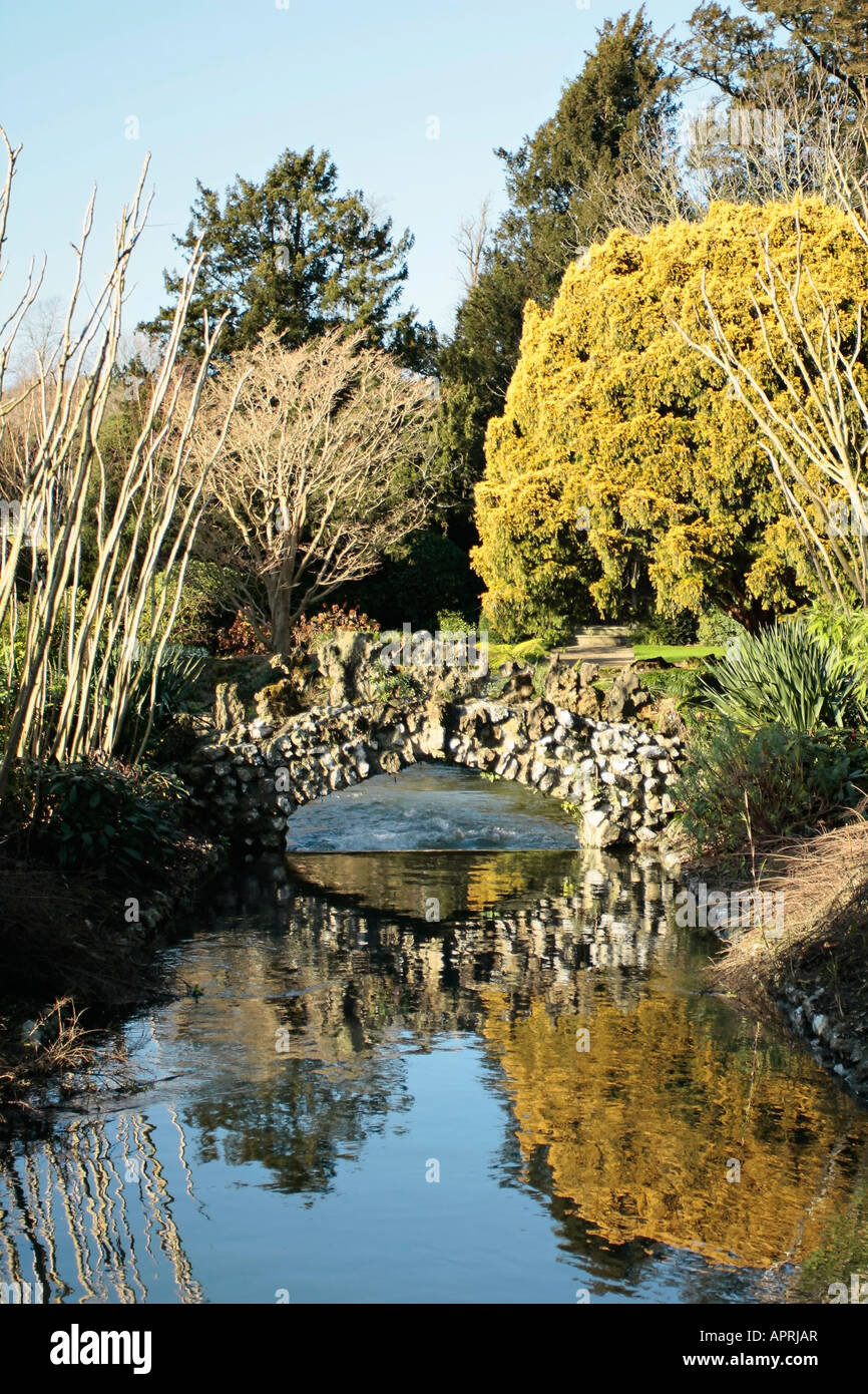 Pont en pierre ornementale sur le ruisseau en hiver à West Dean Gardens, West Sussex, Angleterre Banque D'Images