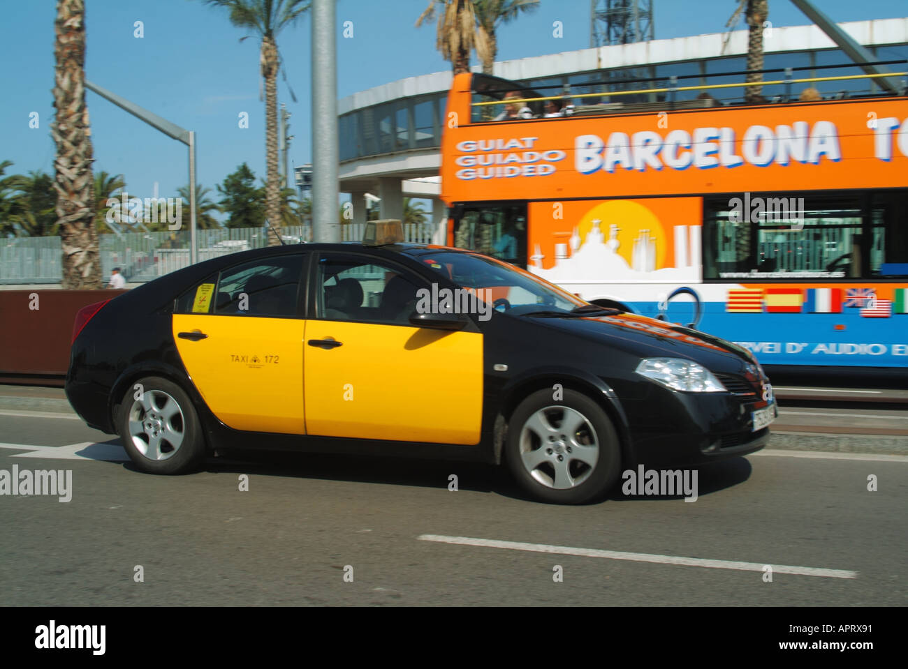Vue latérale de l'emblématique taxi espagnol jaune et noir et chauffeur passant par un bus touristique à toit ouvert de Barcelone dans la rue Catalogne Espagne UE Banque D'Images
