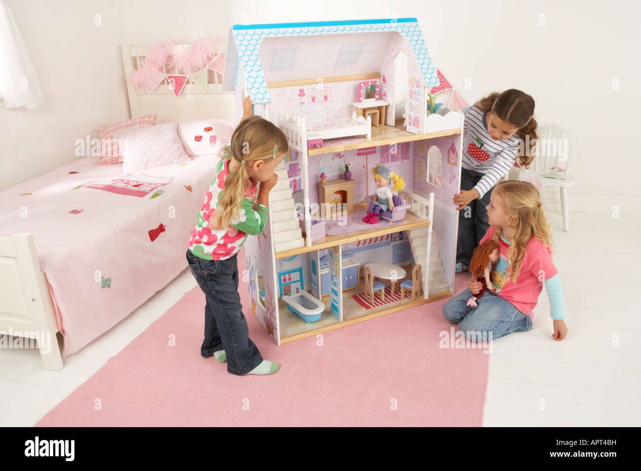 Trois jeunes filles jouer dans une chambre avec une maison de poupées Banque D'Images