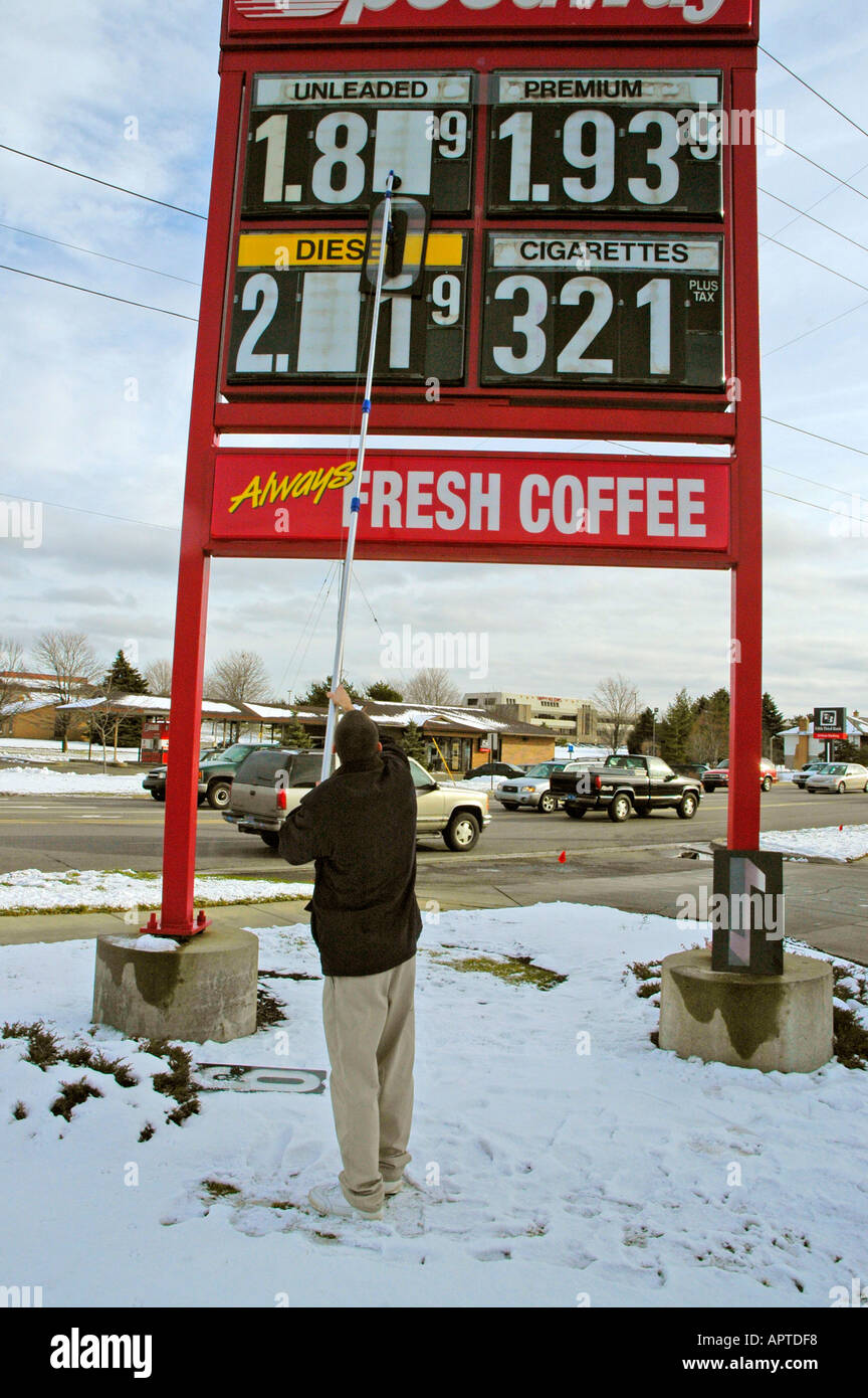 Station de gaz employé change le montant payé pour un gallon d'essence sur un signe extérieur d'une station de gaz Banque D'Images