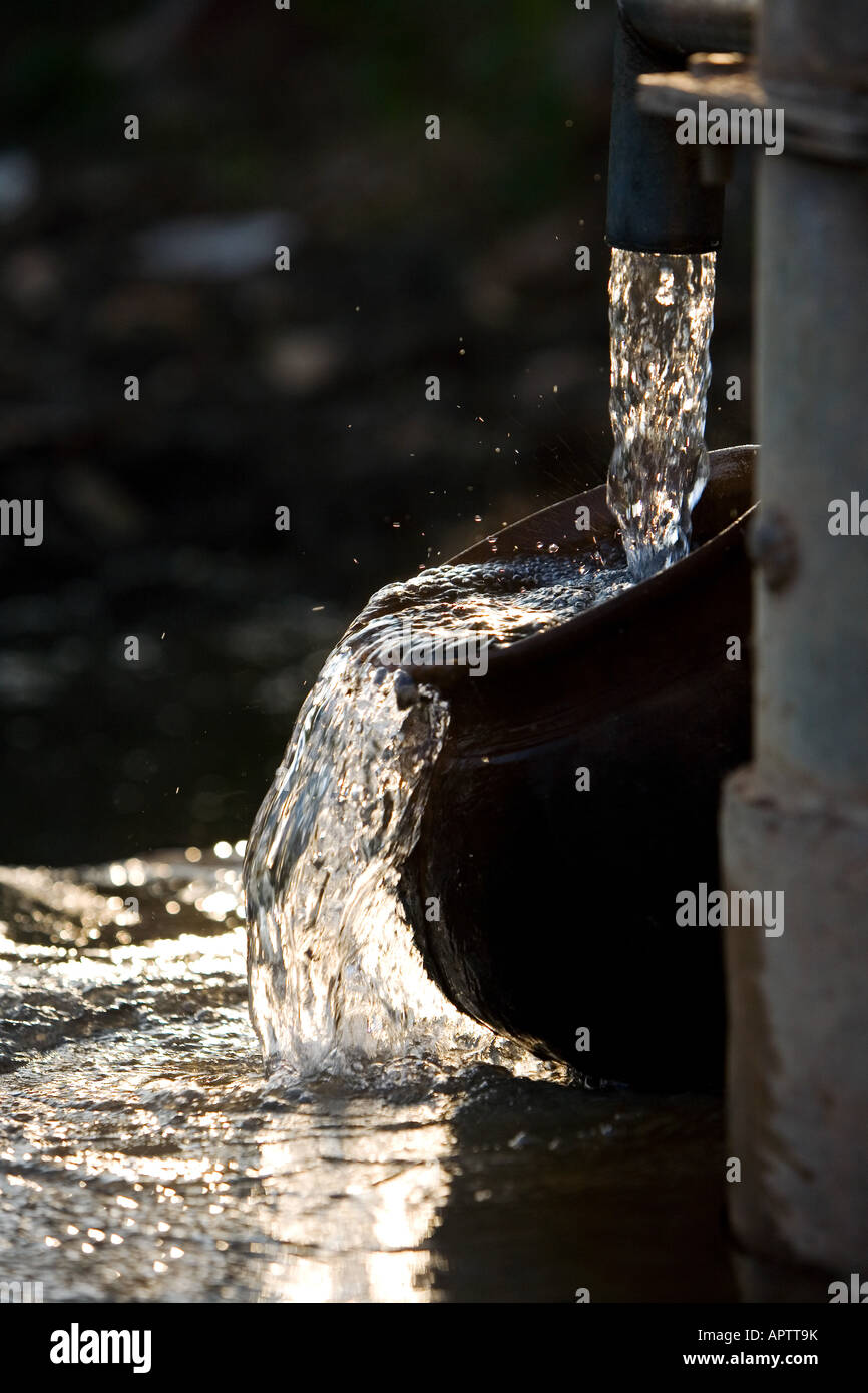 Remplissage d'un Indian Clay pot avec de l'eau propre et fraîche à une pompe à eau à main dans la campagne indienne. L'Andhra Pradesh, Inde Banque D'Images