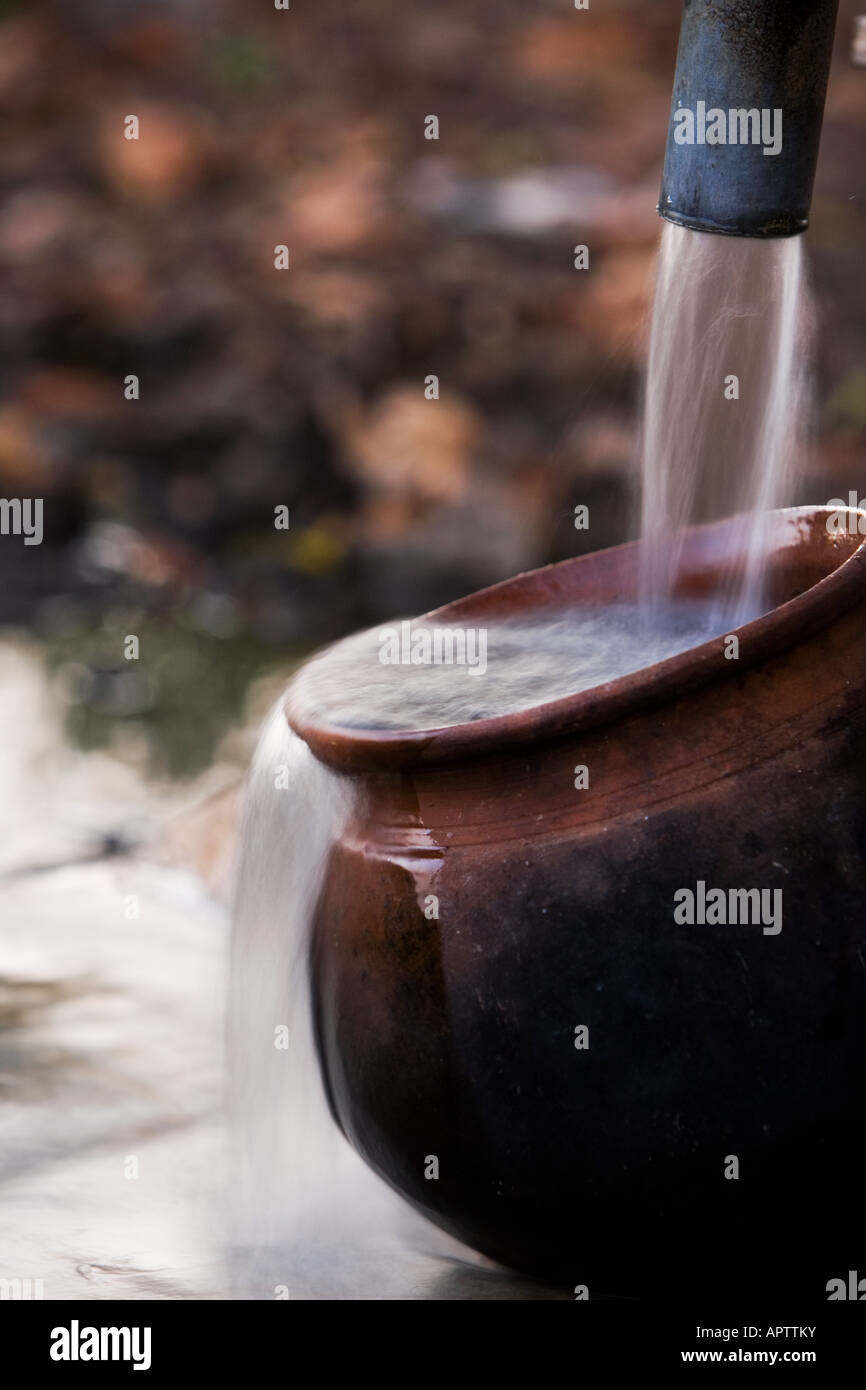 Remplissage d'un Indian Clay pot avec de l'eau propre et fraîche à une pompe à eau à main dans la campagne indienne. L'Andhra Pradesh, Inde Banque D'Images